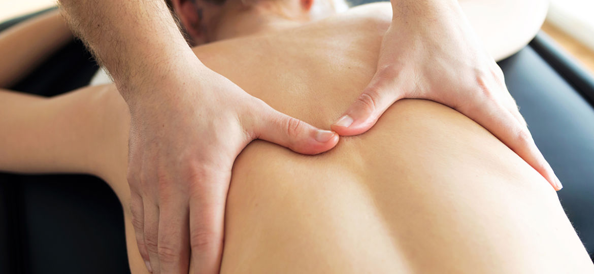 Young physiotherapist doing a back treatment to the patient in a
