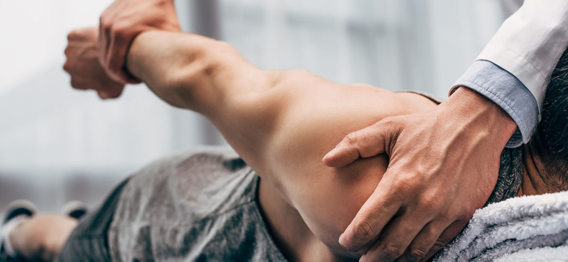 selective focus of chiropractor stretching arm of patient in hos