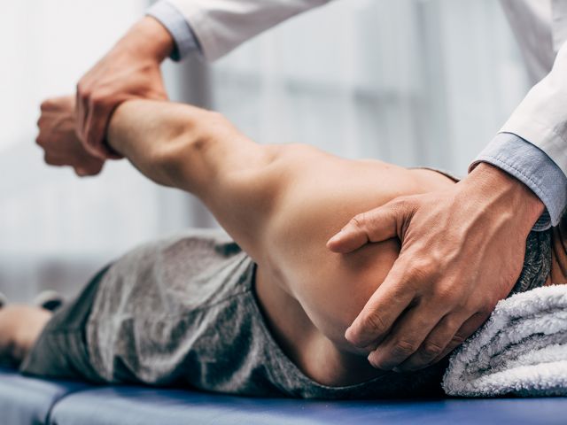 selective focus of chiropractor stretching arm of patient in hos