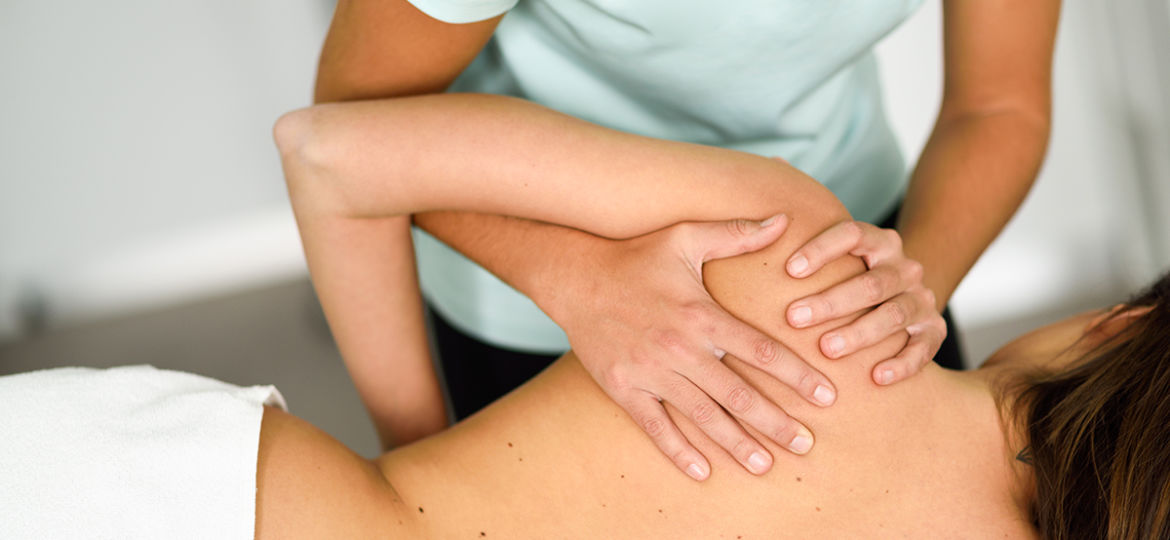 Professional female physiotherapist giving shoulder massage to a