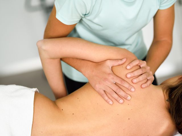 Professional female physiotherapist giving shoulder massage to a