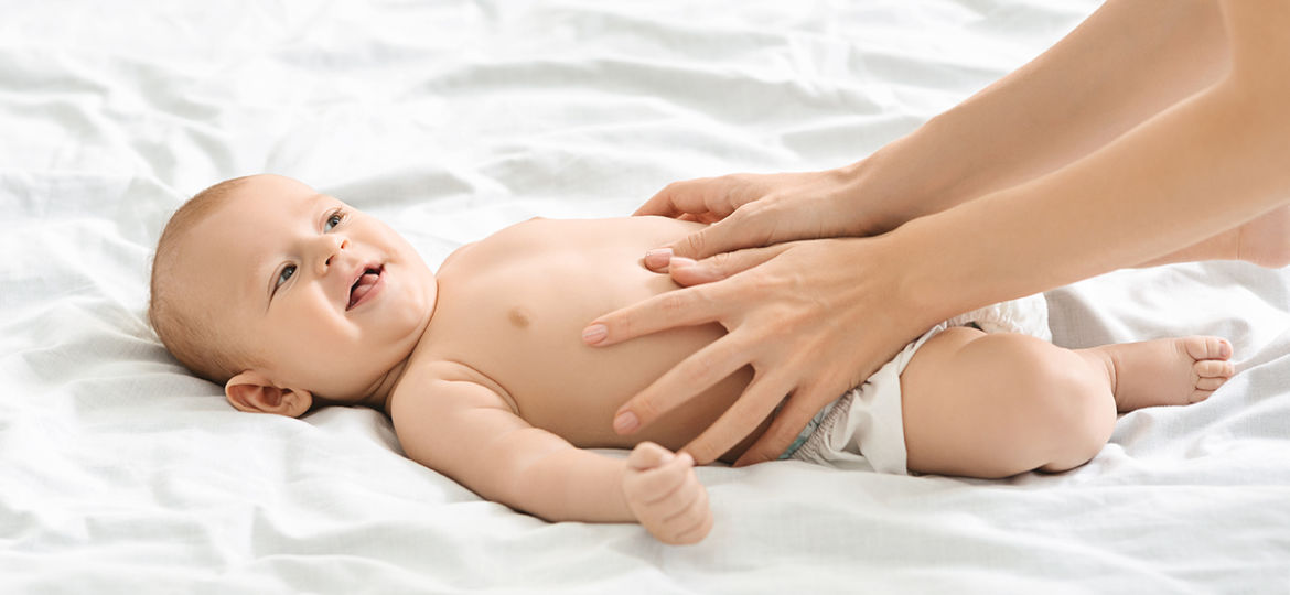 Mother massaging tummy of newborn baby to prevent colics