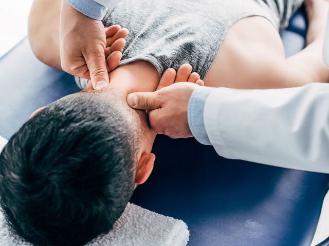 chiropractor massaging neck of man lying on Massage Table with t